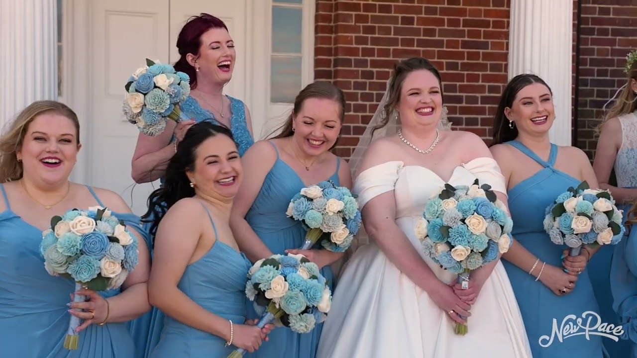 A bridal party of bridesmaids in blue dresses and a bride laugh together holding bouquets, captured at a Love & Light Entertainment wedding.