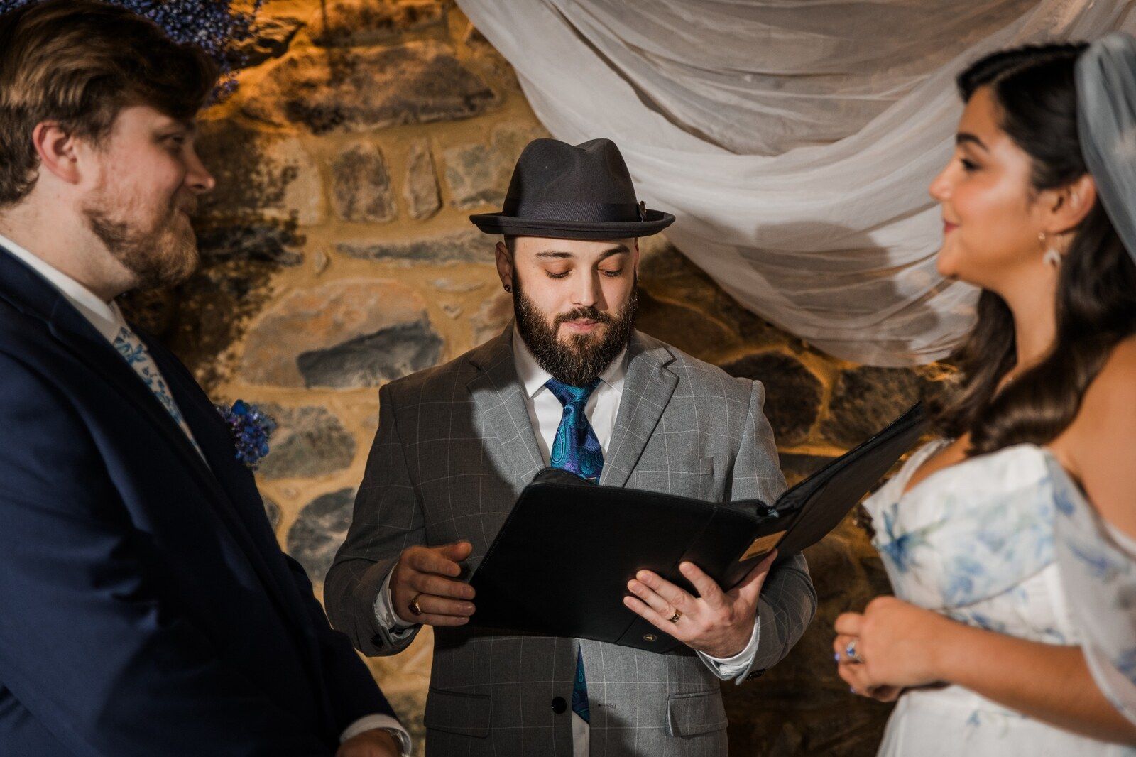 Joshua Pelling officiates a wedding ceremony as the couple faces each other beside him.